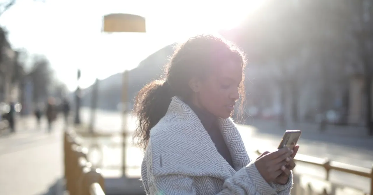 A traveler checking their smartphone's signal in a busy city street at dusk