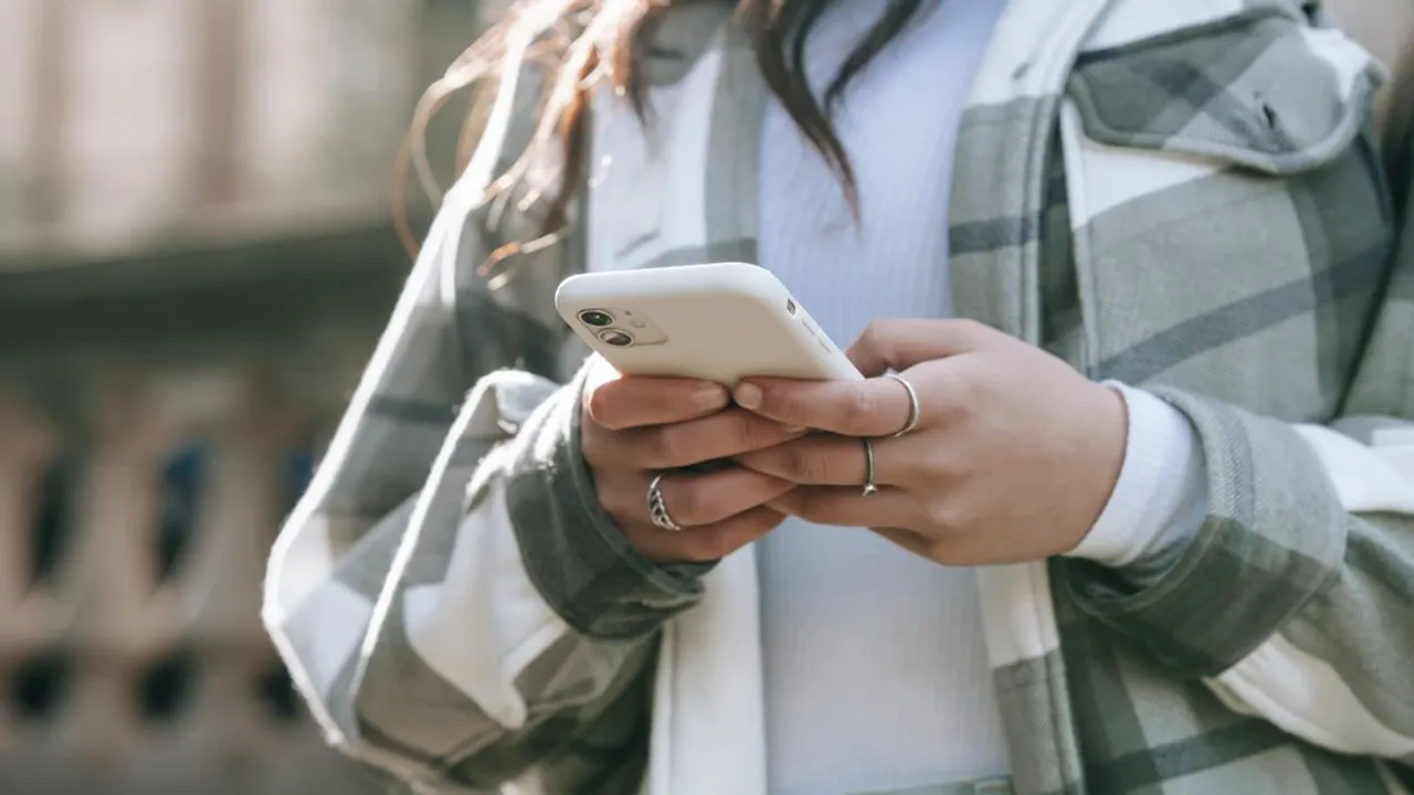 A traveler checking her phone's signal while walking down a city street