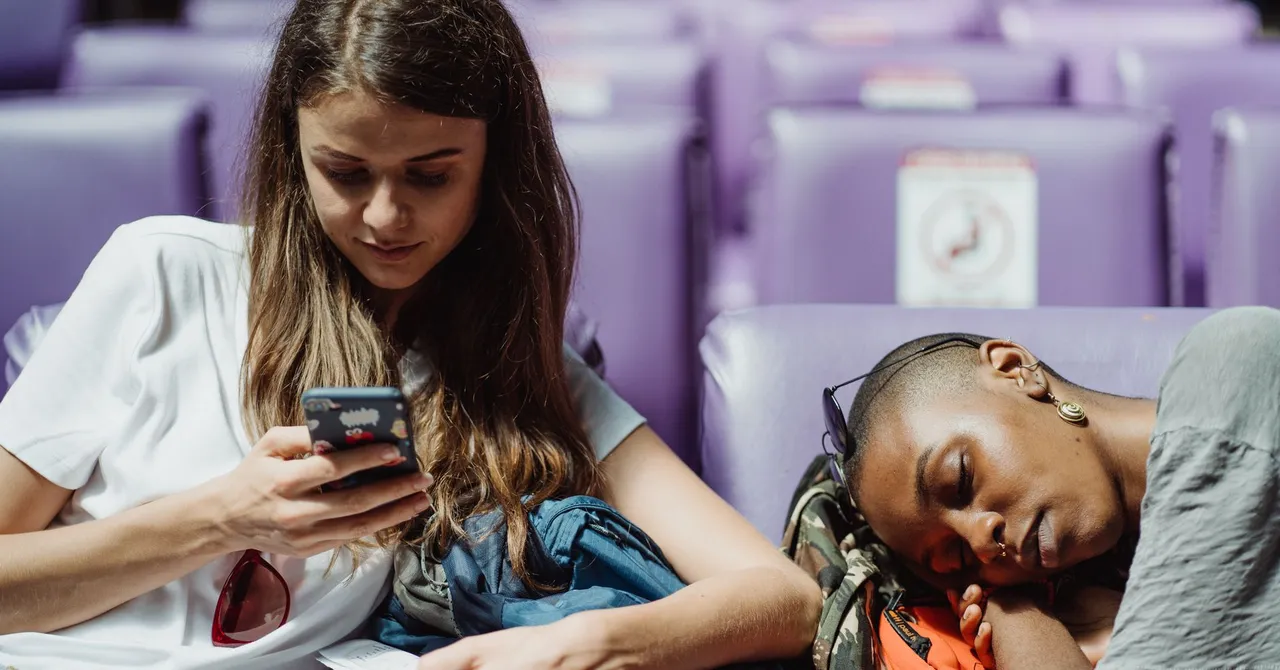 A traveler checking her smartphone while waiting at a station