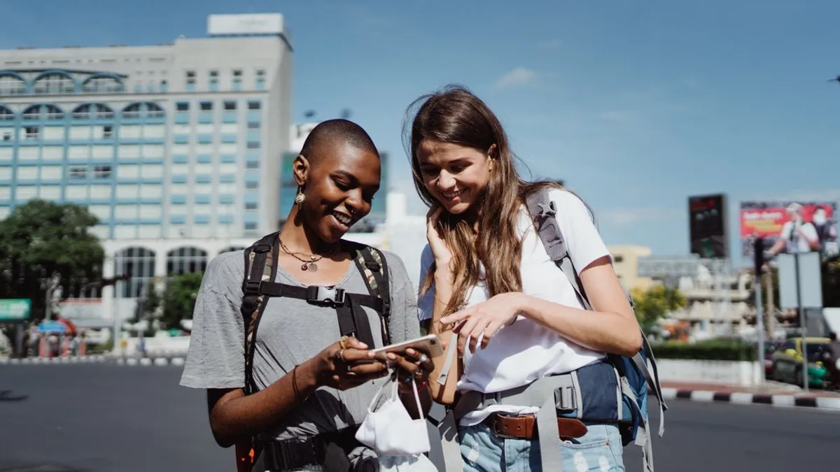 Two travelers checking a smartphone together on a city street