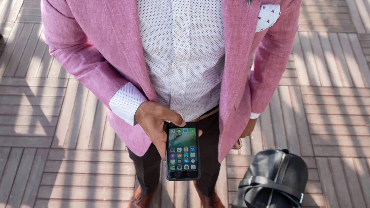 A traveler checking his phone for an email while carrying luggage