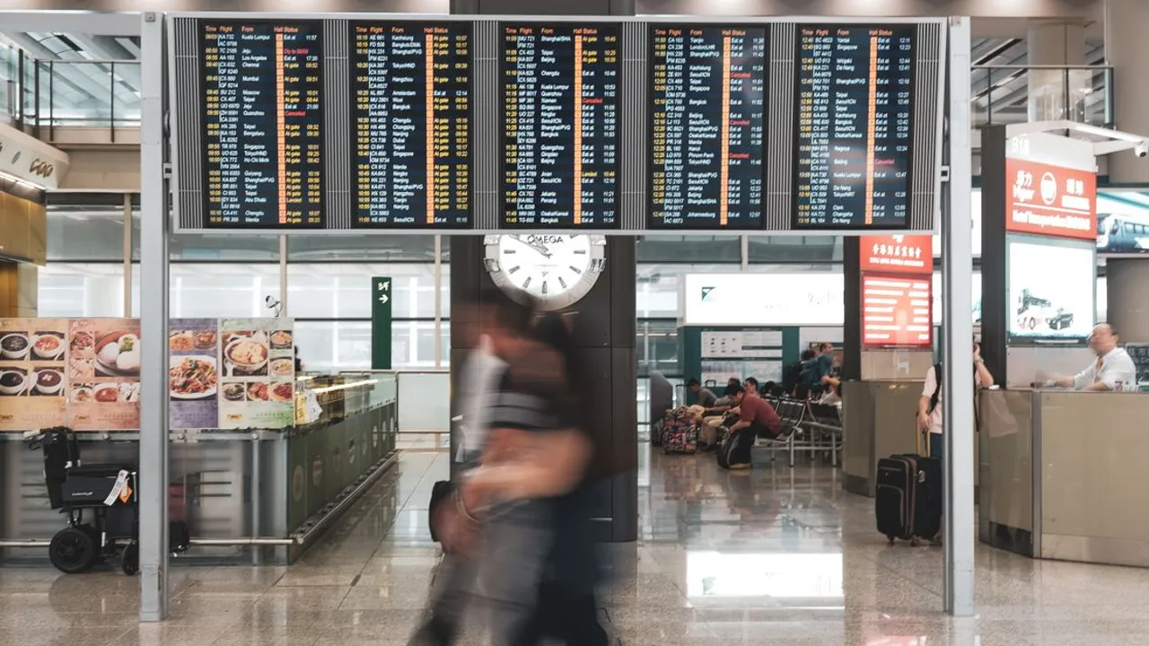 A departure board listing flights to dozens of cities across Asia in a busy airport terminal