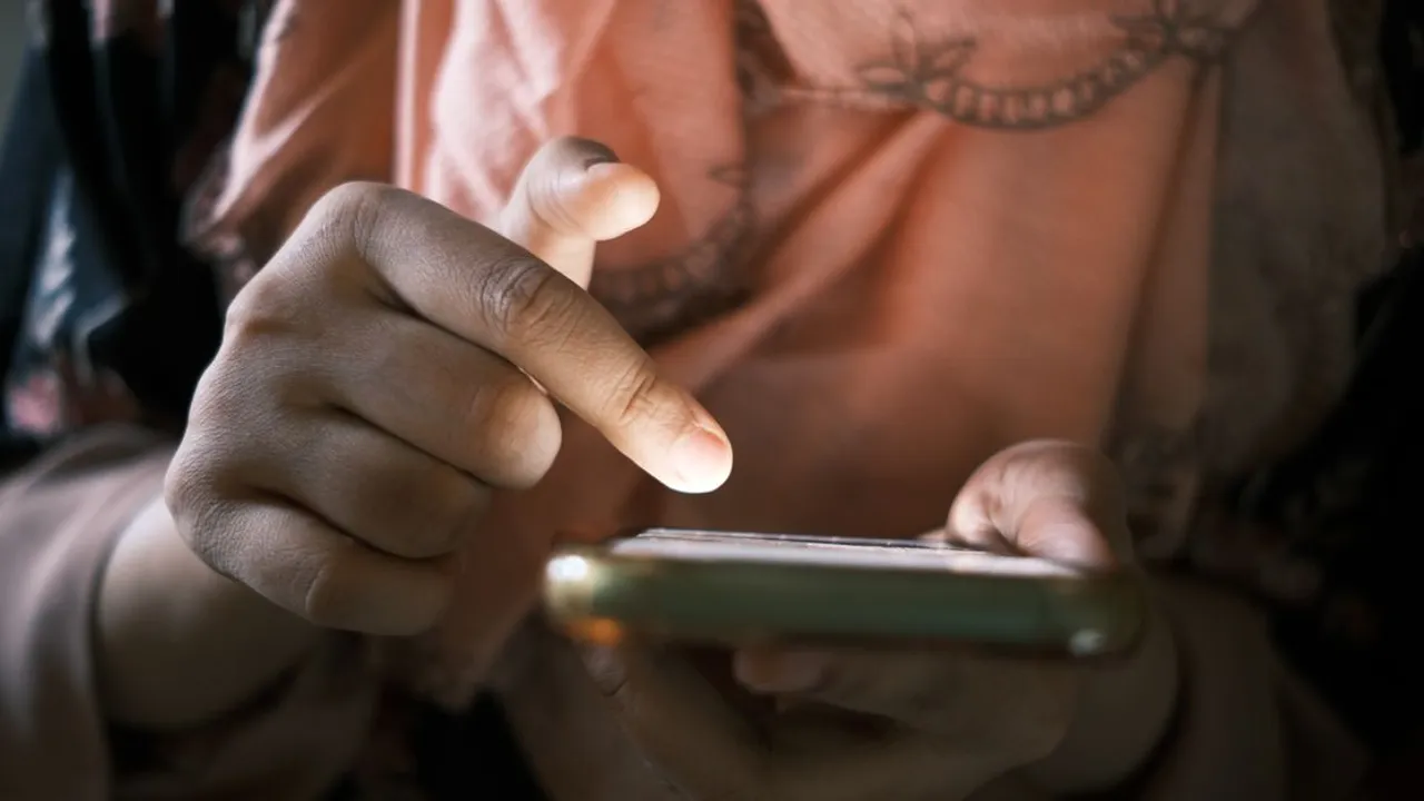 Close-up of hands scrolling through a smartphone's settings screen