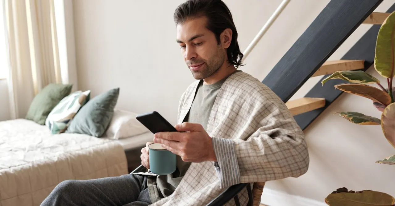 A traveler relaxing at home with coffee while using their smartphone on a stable Wi-Fi connection