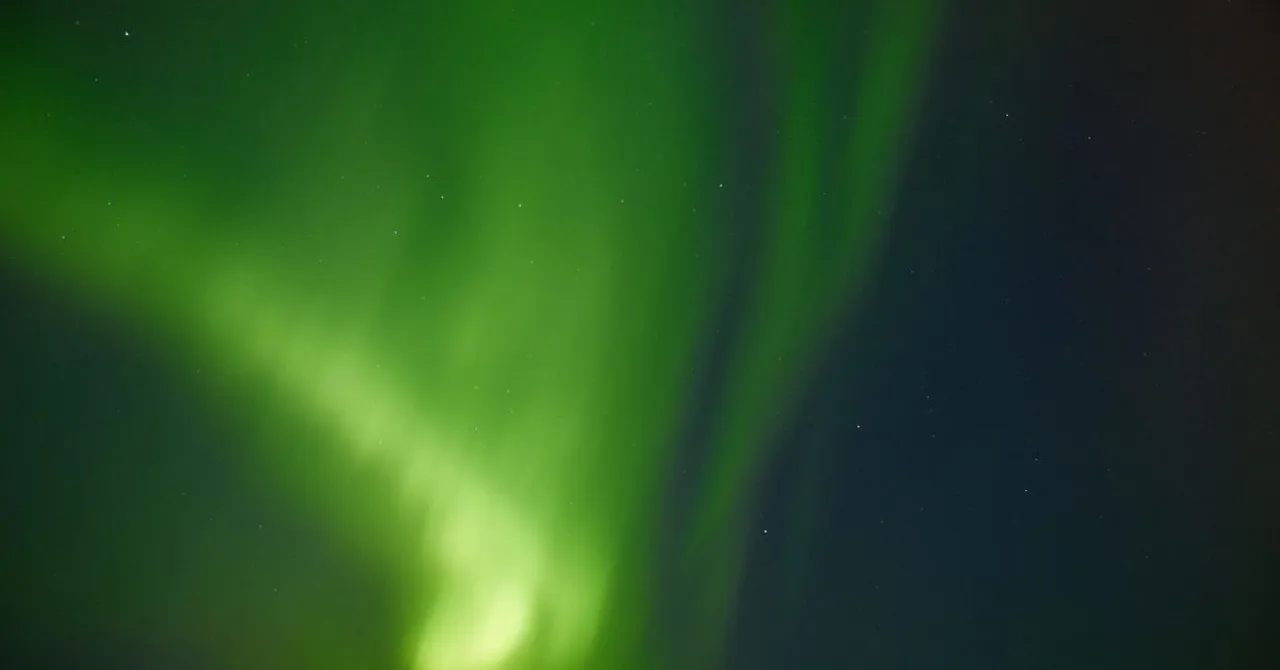 A vivid green aurora borealis glowing across a dark night sky in Iceland