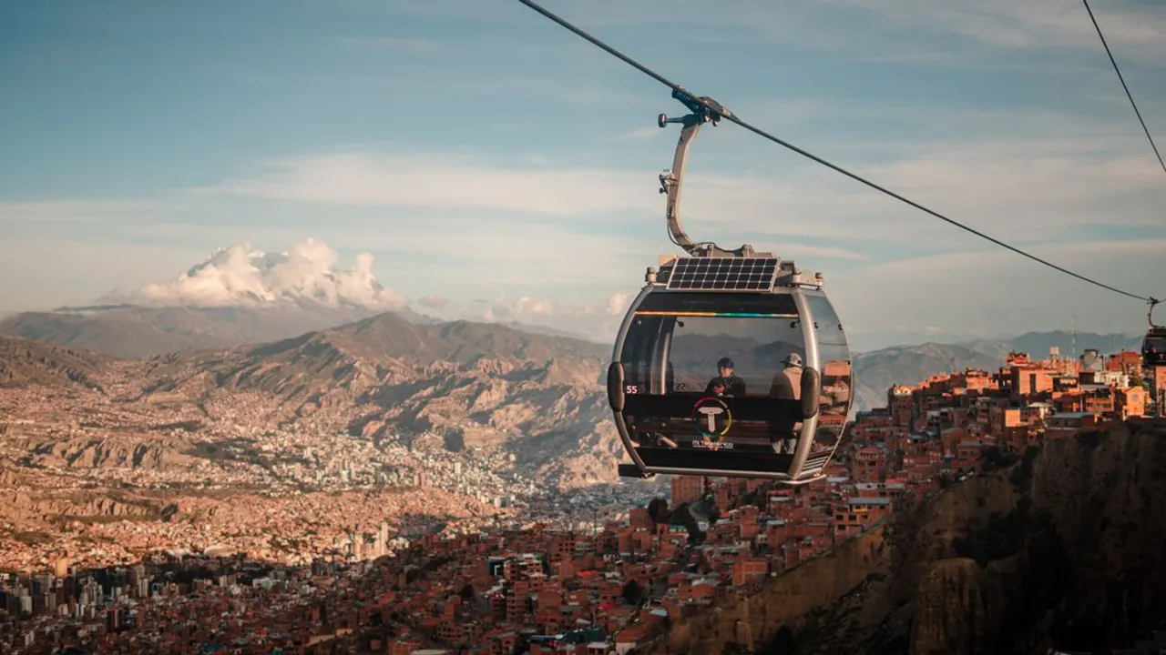 A cable car of La Paz's Mi Teleférico system glides above the city's steep canyon neighborhoods with the Andes in the distance
