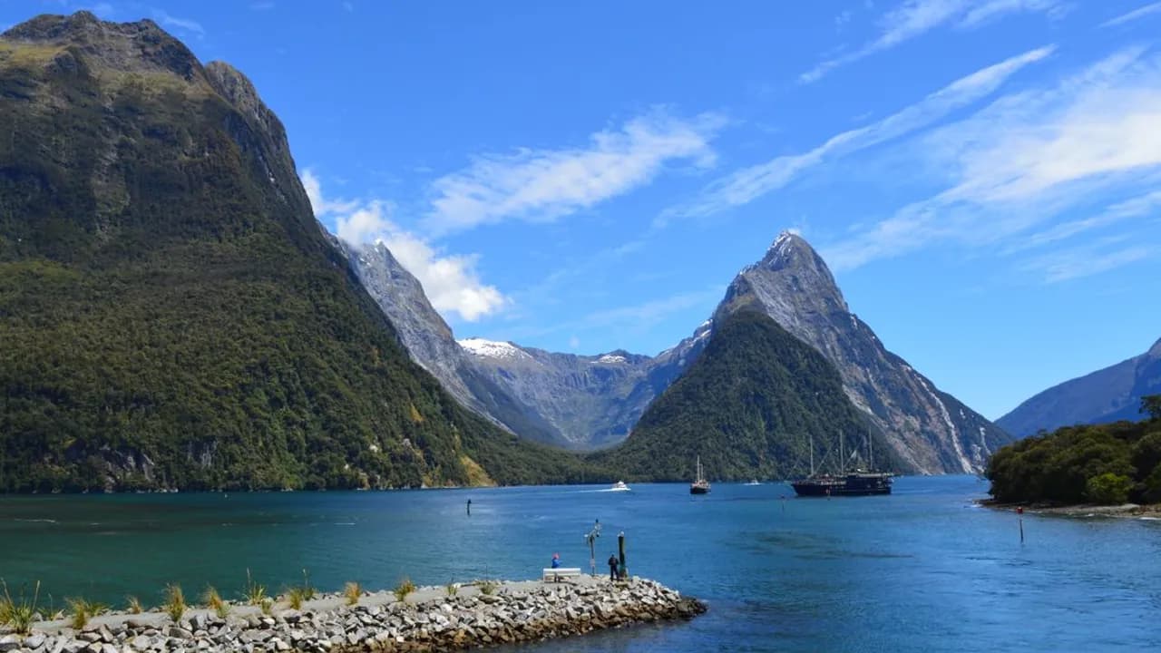Steep, forested fjord walls rising straight out of still water in Fiordland National Park, New Zealand