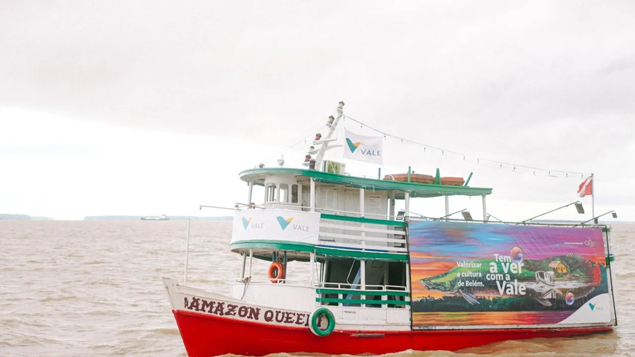 A colorful riverboat navigating a wide river through dense rainforest
