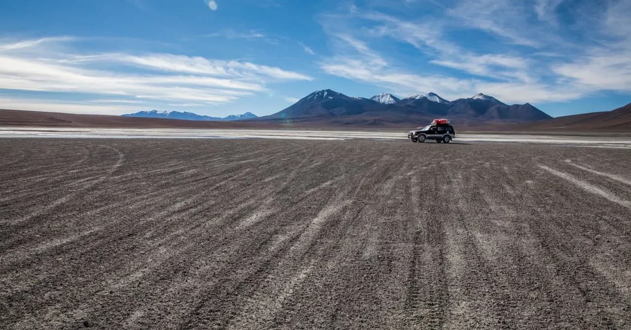 Eine Schotterpiste quert den hochgelegenen Altiplano der Anden unter weitem Himmel