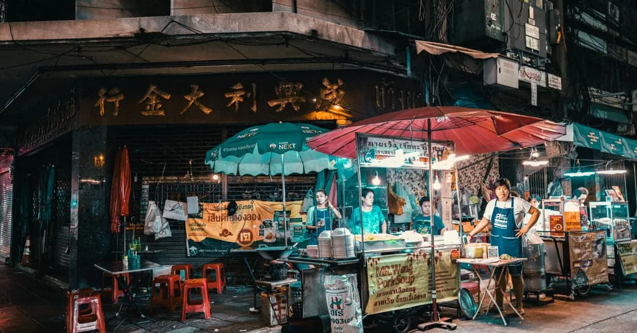 Garküchen unter Markisen in einer Straße in Bangkok bei Nacht