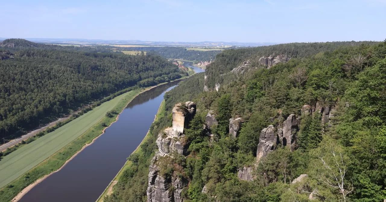 De Elbe die zich een weg baant tussen beboste zandsteenrotsen in Saksen, het landschap waar de lijn Berlijn-Praag doorheen loopt.