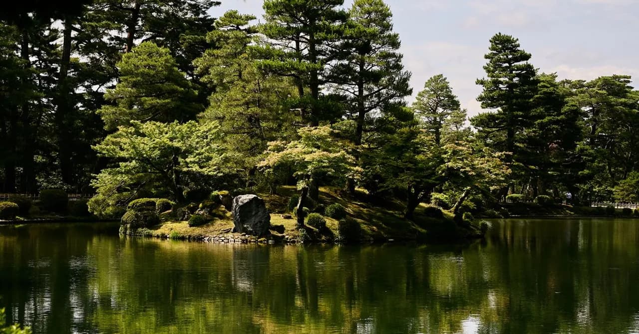 A traditional Japanese strolling garden with a pond, stone lanterns and pruned pines