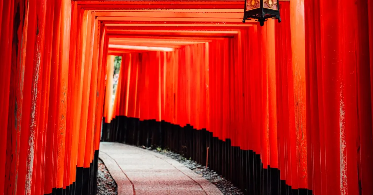 A tunnel of vermilion torii gates on a stone path at a Kyoto shrine