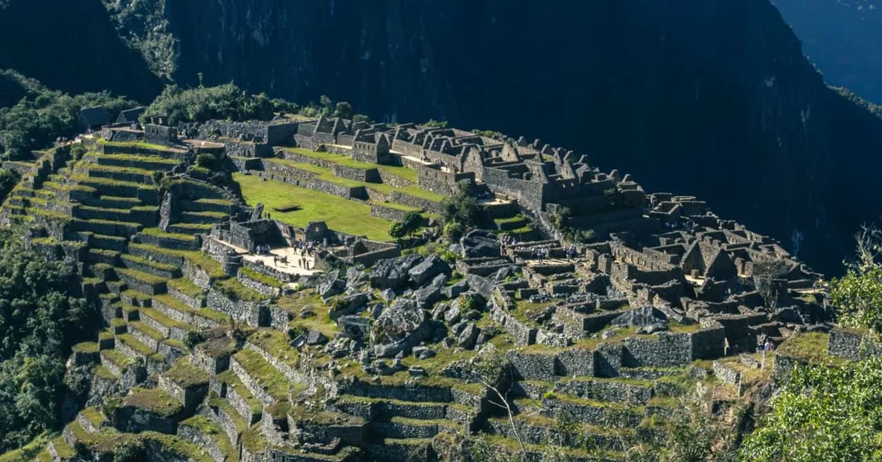 Terrassen und Steinbauten von Machu Picchu vor steilen grünen Bergspitzen