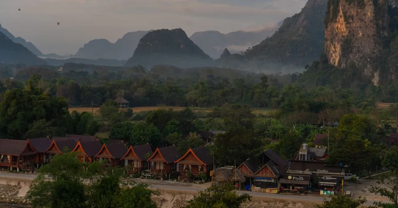 Pinnacoli calcarei che si alzano sopra un fiume e un villaggio in Laos